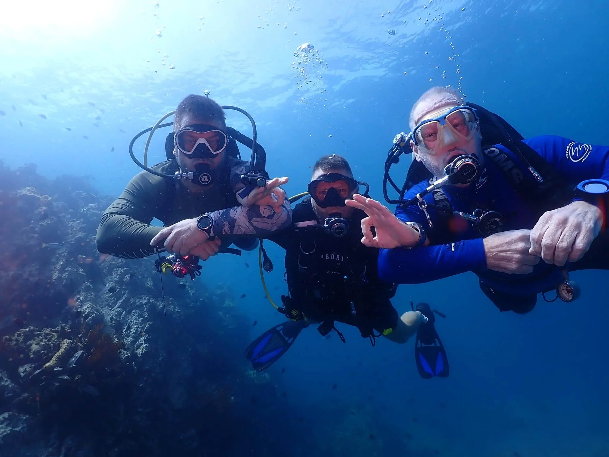 Drei Taucher mit Tauchmasken und Atemreglern unter Wasser
